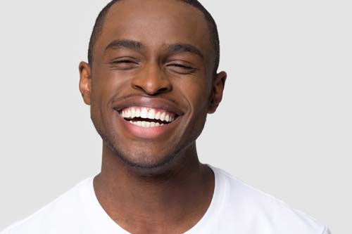 Young man smiling with bright white teeth after teeth whitening treatment at Cascadia Family Dental in Bend, OR