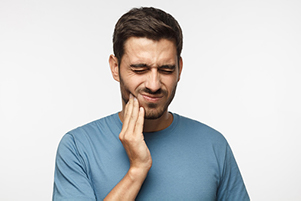 Young man holding his cheek in pain, needing dental fillings from Cascadia Family Dental in Bend, OR.